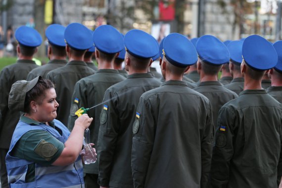 Жінка-військовослужбовець президентської бригади Національної гвардії обприскує водою солдатів. Вони вишикувалися в колони на столичному Хрещатику 20 серпня. Тренувалися проходити строєм на параді до Дня Незалежності. Тоді температура в місті сягала 30 градусів
