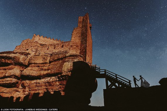 Пара позирует на фоне с испанского замка в Перасенсе и звездным небом позади них