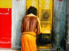 Мужчина молится у двери храма легендарного города Варанаси, Индия