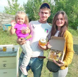 Анастасія та Олексій Конюші з донькою Мирославою стоять біля власної пасіки в селі Бобриця Канівського району на Черкащині