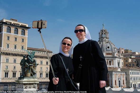 Поллі Русин зняла монахинь, які робили селфі, в Римі у квітні 2018-го. "Я дуже хотіла сфотографувати черниць в Римі. Зустріла цих двох в останній день моїх римських канікул. Монашки виглядали круто в сонцезахисних окулярах, щасливі робили селфи. Я стала перед ними і зробила пару знімків. Хотіла, що вони не помітили, що я їх фотографую. Та вони помітили. Ми обмінялися посмішками і помахали одне одному. Я люблю цей знімок, бо він показує, що черниці у відпустці такі ж люди, як і ми", - розповіла автор