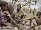 Подростки из племени Хадза сидят у костра и жарят мясо бабуина на озере Эяси на севере Танзании