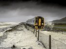 Знімок потяга, який проїжджає по коліях, затоплених морською водою, зроблено в жовтні 2017 року в Тайвіні в штаті Уельс. Автор Пауль Фоулс