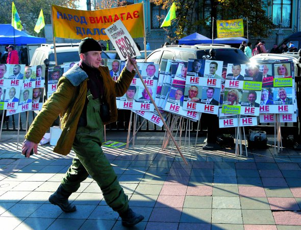 Чоловік проходить повз таблички із прізвищами та фотографіями народних депутатів і написами: ”Не визначився”. 8 листопада власники автомобілів з іноземною реєстрацією під Верховною Радою вимагали спростити та здешевити ввезення з-за кордону машин