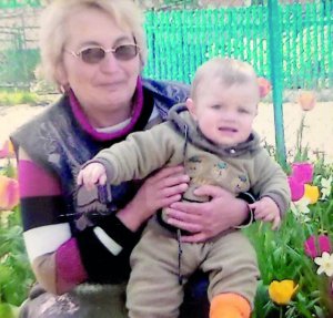 Емілія Ткачук із селища Демидівка на Рівненщині сидить з онуком Русланом у власному дворі