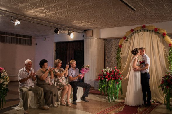Аліна та Ігор Лещина цілуються під час весілля цього літа у громадському центрі біля мінного поля в Авдіївці