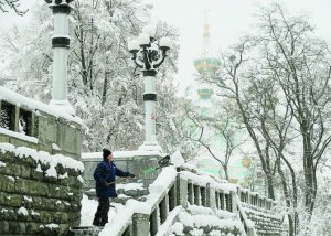 Чоловік прибирає сніг біля Андріївської церкви у Києві. Сніжитиме до березня. Найбільше похолодання в Україні цієї зими настане в лютому. Тоді температура опуститься до 22–25 градусів нижче нуля