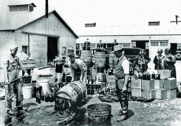 Чоловіки виливають вино на одному зі складів у США під час дії сухого закону у 1919–1933 роках
