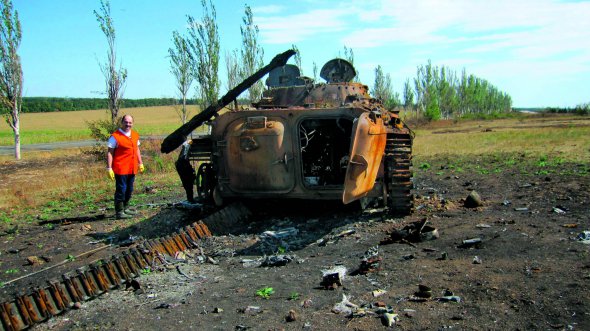 Військовий пошуковик Ігор Слюсар стоїть біля розбитої БМП під час першого виїзду з евакуації тіл загиблих у районі Савур-Могили на Донеччині, 3 вересня 2014 року. Тоді вперше побачив обвуглене людське тіло