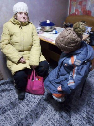 Антоніна Бондар з онуком Артемом сидить вдома у волонтера Світлани Пенкалі. До неї прийшли колядувати. Живуть у двокімнатній квартирі  з десятьма родичами