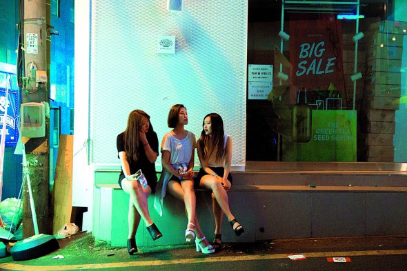 Дівчата сидять біля магазину у столиці Південної Кореї Сеулі