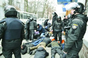 Працівники поліції затримують учасників акції ”Хто замовив Катю Гандзюк” на Контрактовій площі в Києві 9 лютого. Повезли їх до райвідділу перевіряти, чи не перебувають у розшуку. Потім відпустили