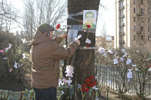Чоловік вішає паперових ангелів до дерева з фотографіями загиблих майданівців на Алеї ­Небесної сотні в Києві вранці 19 ­лютого. ­Загиб­лих героїв прийшли ­вшанувати майже 200 людей