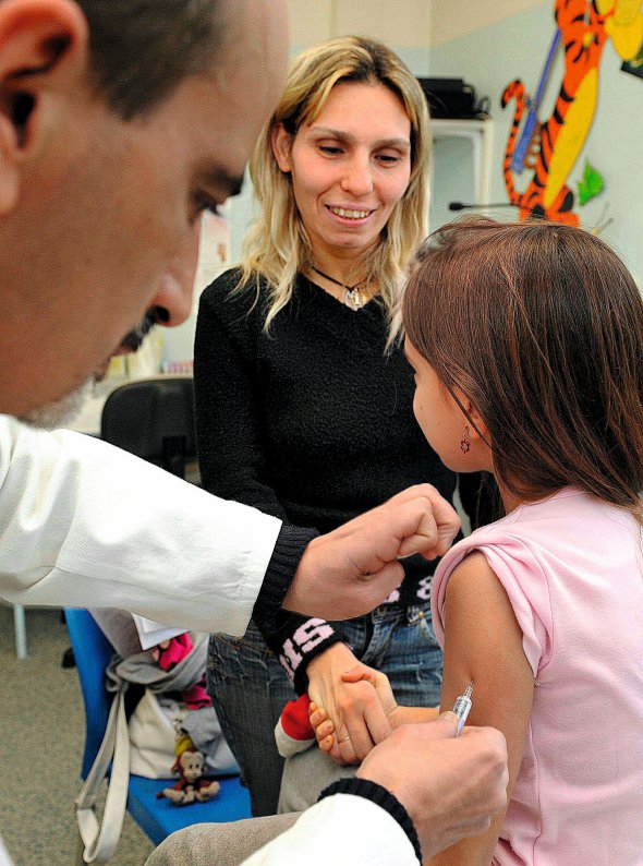 Лікар робить щеплення дівчинці у клініці в Римі. Батькам пропонують здати аналіз на наявність у малюків антитіл до кору. Вакцинують від нього безкоштовно