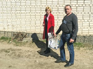 Член виборчої комісії Леся Муха та водій Віталій Кристофорич несуть скриньку для голосування тим, хто не зміг прийти на виборчу дільницю за станом здоров’я