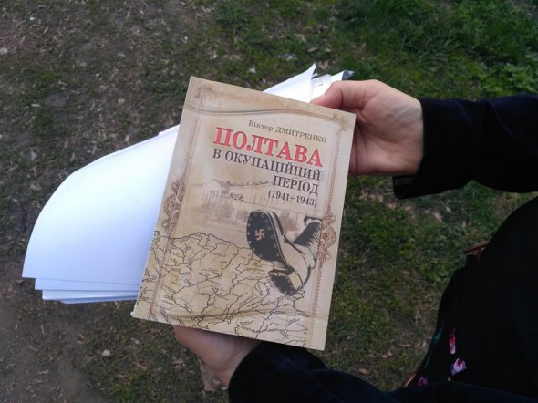 Олександра демонструє невелику книжку авторства Віктора Дмитренка в паперовій палітурці. З поміж іншого там є інформація і про німецький концтабір.