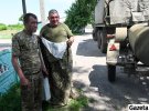 Волонтери передають військовим плащ-палатки і солодощі. Бійця справа звуть Василь. Разом із ним служить син