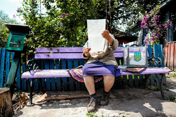 Жінка вивчає виборчий бюлетень перед тим, як кинути його в переносну урну під час парламентських виборів у селі Перше Травня Броварського району Київської області 21 липня