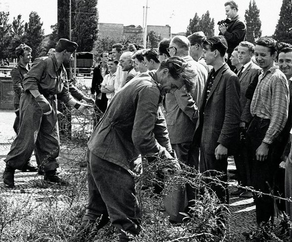 Солдати розмотують колючий дріт на берлінській вулиці 13 серпня 1961 року. Відділили частину міста, яку контролює СРСР. За два дні вздовж цієї лінії почали зводити бетонну стіну заввишки до 5 м і довжиною 45 км. До листопада 1989-го жителів Східного Берліна не випускали в Західний