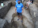 Археолог Алексей Крютченко демонстрирует туристам найденный утром детский скелет