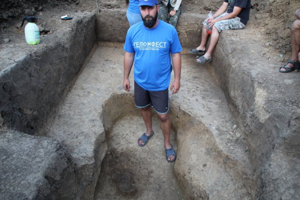 Археолог Алексей Крютченко демонстрирует туристам найденный утром детский скелет