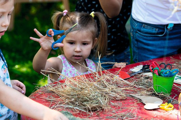 Дівчинка під час майстер-класу ріже ножицями солому й картон для виготовлення іграшкових пташок. Захід на фестивалі високого мистецтва Bouquet Kyiv Stage провела арт-майстерня "Дім МК" 25 серпня 2019 року