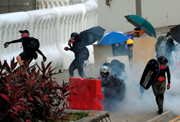 Протестувальники  в Гонконгу закриваються парасольками  від сльозогінного газу  під час протестів  у серпні. Кидали  в силовиків каміння