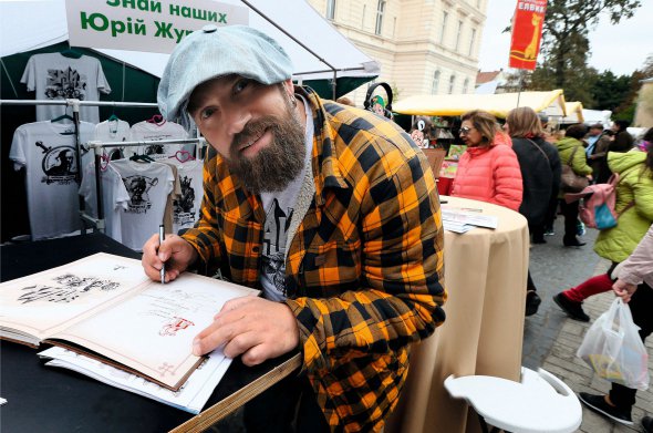 Музикант і художник Юрій Журавель ставить автограф на своїй книзі "Знай наших"