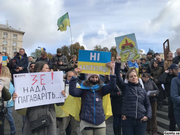 Участники акции слева от сцены. На одном из плакатов зеленая лягушка в российском традиционном кокошнике