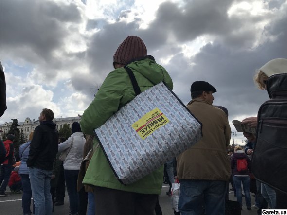 На сумке женщины наклейка "Остановить капитуляцию"