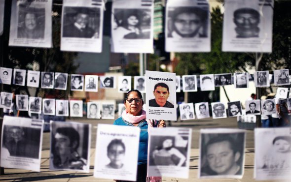 Жінка тримає фото сина на акції під офісом поліції у столиці Мексики Мехіко. Люди просили розслідувати зникнення  їхніх родичів