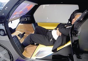 Представник японської фірми ”Тойота” на міжнародному автосалоні в Токіо демонструє, як можна відпочити під час поїздки в новому електричному автомобілі компанії. Машина оснащена автопілотом. У салоні є телевізор