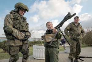 Хлопчик тримає кулемет "ПКМ" на виставці військової техніки під час церемонії ­присяги новобранців російського військово-патріотичного клубу "Юнармія" у чорноморському порту окупованого Севастополя