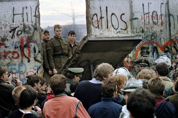 Прикордонники Східної Німеччини дивляться через отвір у Берлінській стіні після того, як демонстранти зірвали фрагмент муру біля Бранденбурзьких воріт, 11 листопада 1989 року