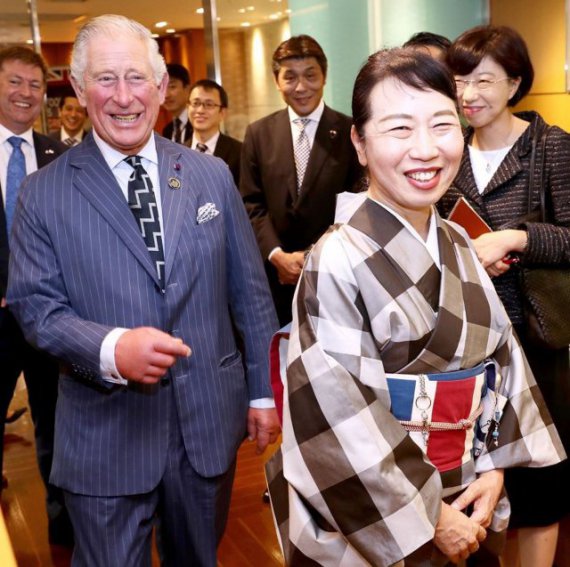 Принц Чарльз смеется вместе с японкой в кимоно, пояс которого напоминает британский флаг