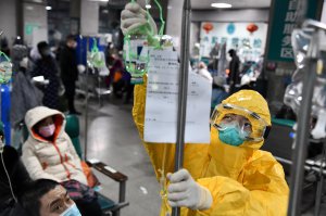 Медик підключає кра­пельницю хворому з симптомами коронавірусу в китайському місті Ухань