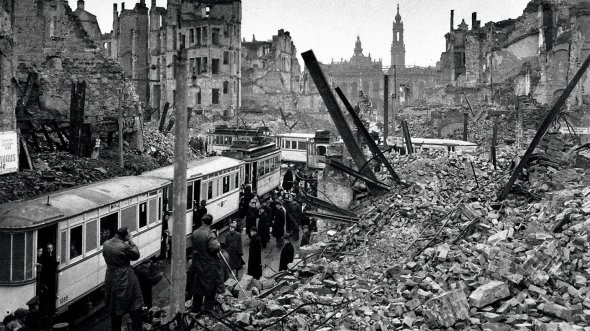Люди розчищають трамвайні колії в німецькому місті Дрезден після бомбардування британськими й американськими літаками 15 лютого 1945-го. Це був найбільш руйнівний авіаналіт Другої світової війни. Операцію почали надвечір 13 лютого. Скинули 1478 тонн фугасних і 1182 тонни запалювальних бомб. Знищили мости, залізниці й автошляхи, половину житлових будівель та чверть промислових. Загинули від 500 тисяч до мільйона людей. Відбудовували місто 40 років