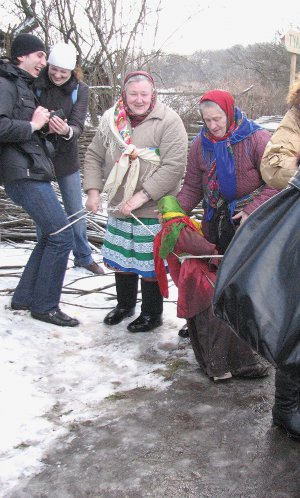 Жінки чіпляють ”колодку” у вигляді ляльки неодруженій парі в селі Пирогів під Києвом, 2008 рік