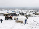 Внутрішньо переміщені люди ходять по снігу біля наметів у імпровізованому таборі в Азазі
