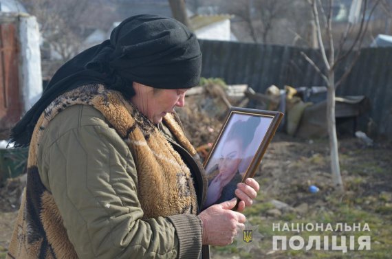 60-річна Ольга Антонівна із Ружина на Житомирщині обіймає портрет онуки 18-річної Анастасії. Її знайшли вбитою у криниці у власному дворі. Підозрюють колишнього дівчини - 22-річного Олександра Савіна
