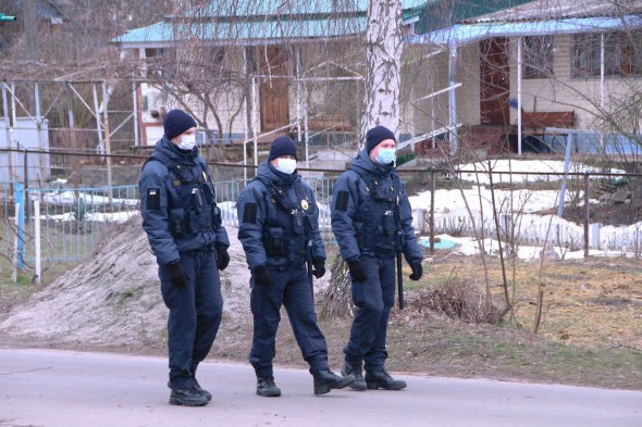 Полицейские патрулируют территорию возле медцентра Нацгваридии в защитных масках на лице