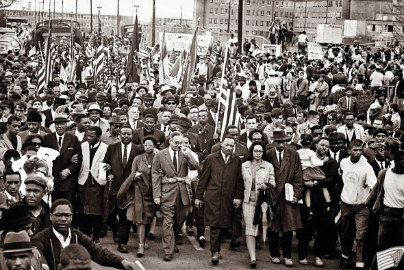 Учасники третього маршу за рівні права білих і темношкірих ідуть центральною вулицею американського міста Монтгомері. В центрі – Мартін Лютер Кінг із дружиною Кореттою. За три роки Кінга в Сельмі застрелив расист Джеймс Ерл Рей. На похорон прийшли 300 тисяч людей