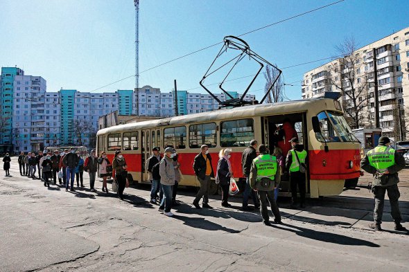 Люди вишикувалися в чергу до трамвая на одній із зупинок у Києві 20 березня. Напередодні громадському транспорту заборонили перевозити одночасно більш як 10 пасажирів. Із 23 березня обмеження посилили