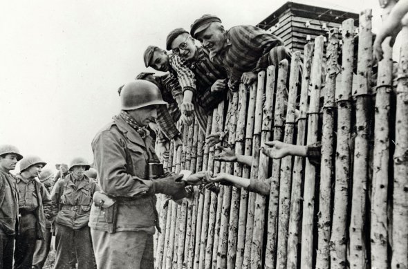 Американський капрал 45-ї стрілецької дивізії роздає цигарки звільненим 11 квітня 1945-го в’язням німецького концтабору Бухенвальд біля Веймара. В ньому від голоду, тортур і медичних експериментів померли 56 тис. людей. За сім днів до приходу американців ув’язнені перебили частину охорони й захопили оглядові вежі