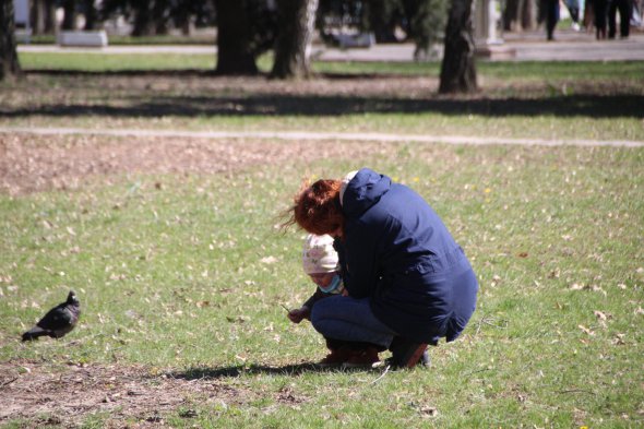 Полтавка гуляет с 3-летней дочерью на газоне, в отдалении от парка и детской площадки