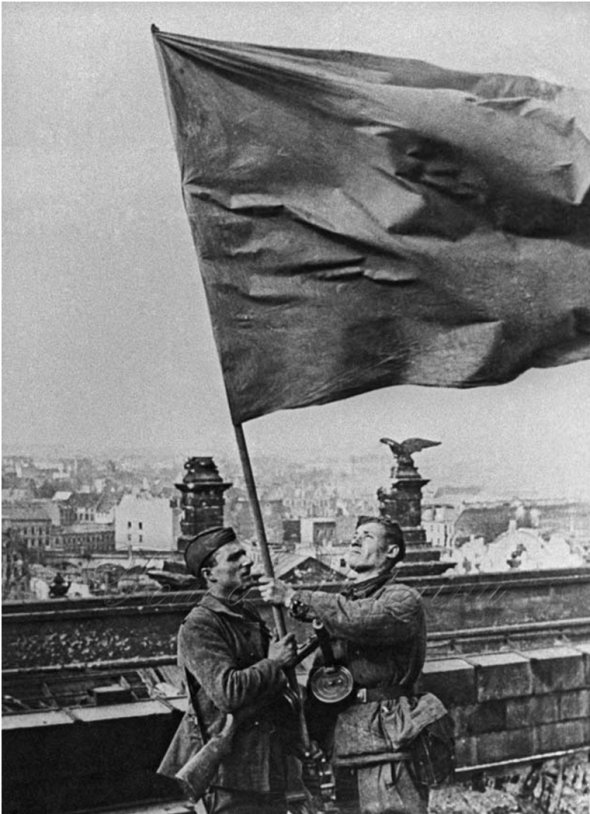 В руках знаменосцев флаг совсем не похож на современное «знамя победы». Это самодельный флаг разведвзвода С.Сорокина, сделанный из немецкой перины.