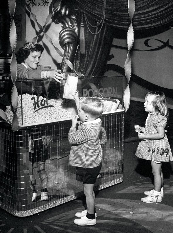 Діти купують попкорн у фойє кінотеатру в Нью-Йорку 17 червня 1946-го. Того року їжу дозволили брати на покази. Повітряну кукурудзу вживали з XVI ст., її на вогні в кошиках із дроту смажили індіанці. Потім стали готувати в парових машинах. Продавали в цирках, на карнавалах і вулицях. У кінотеатрах забороняли, бо глядачі з попкорном смітили і залишали масні плями на кріслах
