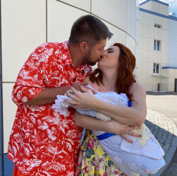 Вікторія Булітко з новонародженою дитиною на руках цілує чоловіка