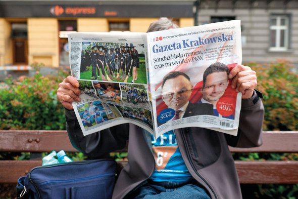 Чоловік читає місцеве видання Gazeta Krakowska, яке на першій шпальті опублікувало результати екзитполів з понад 99 відсотків дільниць про вибори польського президента. Вони показують, що перемагає чинний глава держави Анджей Дуда. Понеділок, 13 липня 2020 року, Краків, Малопольське воєводство, Польща