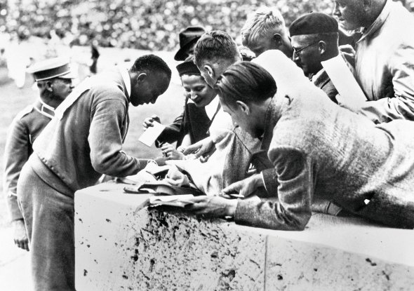 Американський спортсмен 23-річний Джессі Оуенс роздає автографи глядачам під час XI Олімпійських ігор у Берліні, які відкрили 2 серпня 1936-го. Учасниками став 3961 спортсмен із 49 країн. Німці вибороли 89 медалей і посіли перше командне місце, за ними – США та Угорщина. Джессі Оуенс виграв чотири золота у змаганнях із бігу та стрибків у висоту, встановив три рекорди. Адольф Гітлер вітав медалістів, але після перемог темношкірого спортсмена завжди залишав трибуну